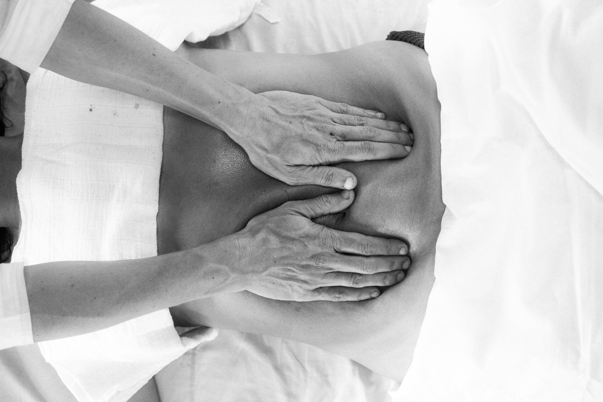 Mãos aplicando manobras do Método Kusum Modak nas costas de uma pessoa